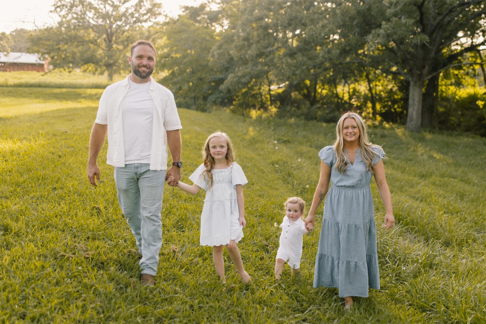 Andrew and Stephanie Newton walking through a field with their two children